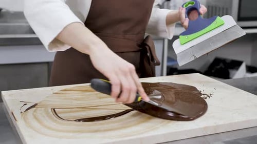 Person Spreading Melted Chocolate in Professional Kitchen