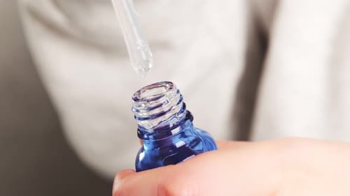 Close Up of Dropper Filling a Blue Bottle