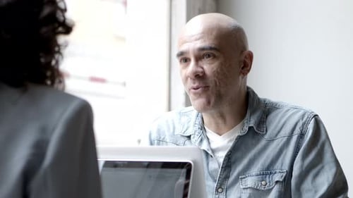 Focused Mature Man Talking with Colleague During Work