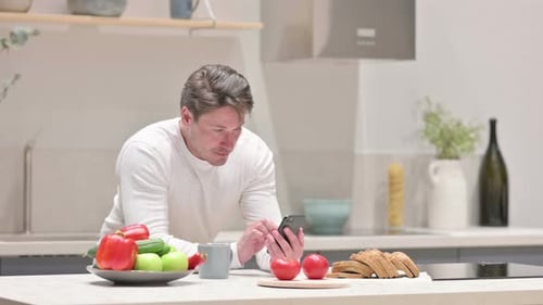 Man Using Smartphone in Bright Modern Kitchen