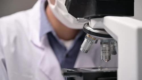 Scientist Examining Sample Under Microscope in Lab