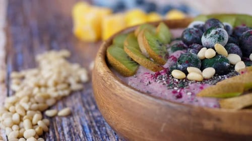 Smoothie Bowl With Fresh And Frozen Blueberries, Kiwi, Banana, Dragonfruit Powder And Pine Nuts.