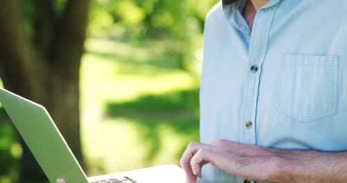 Man using laptop in the park on a sunny day