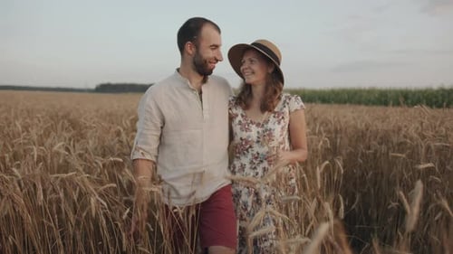 Un couple marié heureux profite d'une promenade en dehors de la ville et s'embrasse dans un champ de blé
