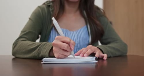 Woman Writing with a Pen in Notebook Indoors