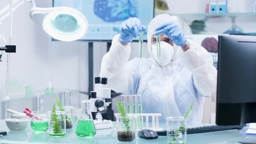 Scientist in Protective Suit Examining Test Tubes