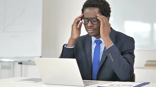 Man in Suit Working on Laptop with Headache