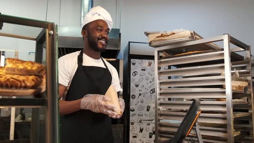 Baker Hands Bag to Customer in Bakery