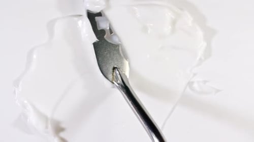 Spreading White Cream with a Spatula on White Background