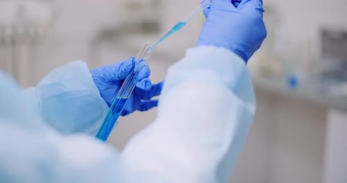 Wissenschaftlerin hält Röhrchen und Flasche mit Flüssigkeit in den Händen
