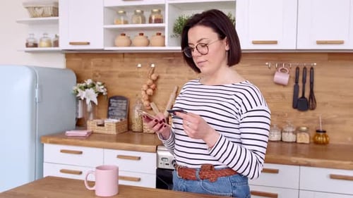 Woman using Smartphone and Credit Card in Kitchen