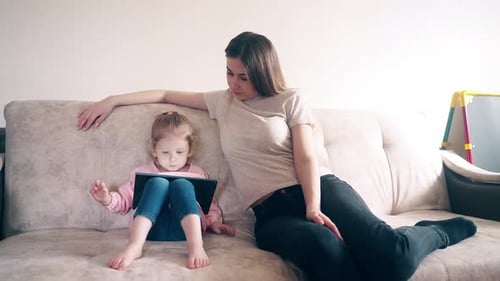 Girl Using Tablet with Woman on Couch