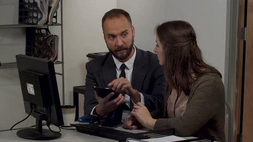 Geschäftsmann und Geschäftsfrau sprechen auf einem Tablet-Computer über Papierkram und Daten.