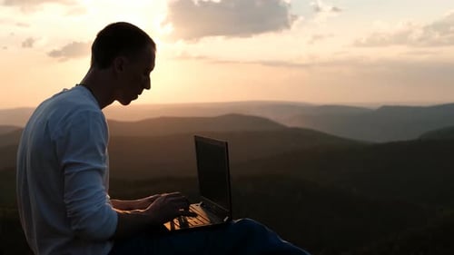 Man Working on Laptop in the Mountains