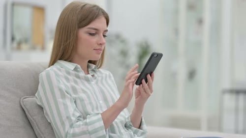 Young Woman Using Smartphone on Couch Indoors