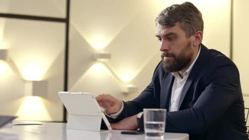 Bearded Man Working on Tablet in Office