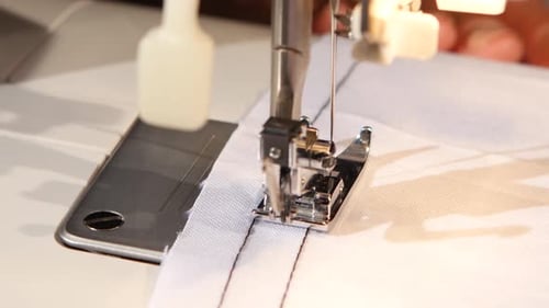 Cousez le tissu blanc de la machine à coudre. Gros plan