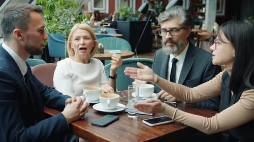 Colleagues Men and Women Talking in Cafe During Business Lunch Discussing Work