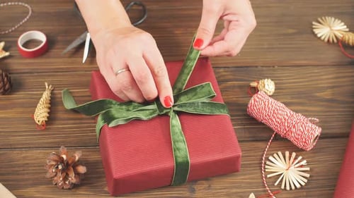 Woman Wrapping Gift on Decorated Wooden Table