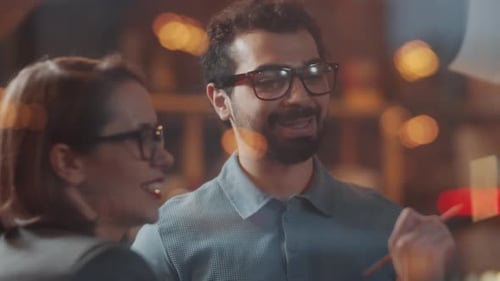 Collègues masculins et féminins parlant et écrivant sur des notes adhésives sur un mur de verre
