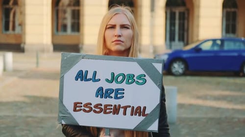 Lors d'une marche de protestation, une femme attire l'attention sur l'importance de tous les types d'emplois