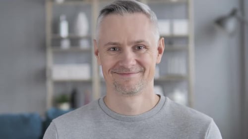 Gray Haired Man Smiling in Front of Shelves