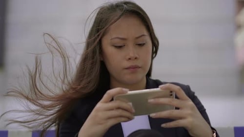 Young Woman Using Phone Outdoors in Windy City