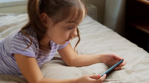 Young Girl Using Smartphone Lying on Bed