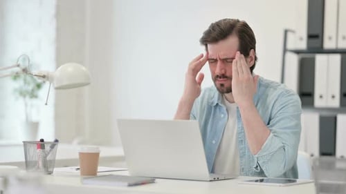 Tired Man Working on Laptop in Office