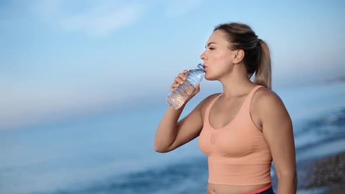 Sportswoman Drinking Water From Bottle After Outdoor Training at Beach