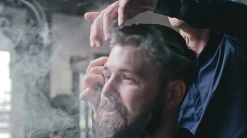 Man Getting Haircut While Vaping in Barber Shop