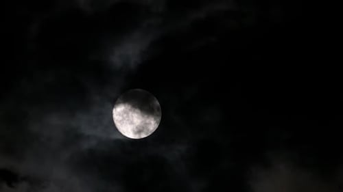 Full Moon Shining Brightly Through Night Clouds