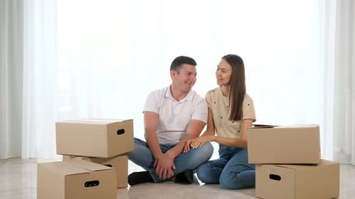 Couple Talking Beside Moving Boxes in New Home