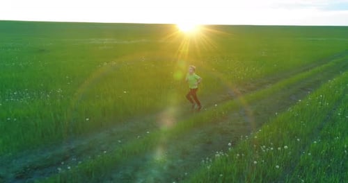Criança desportiva corre através de um campo de trigo verde