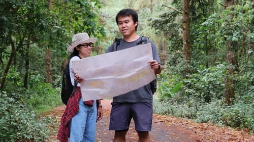 Asian tourist couple with backpacks in a tropical forest.