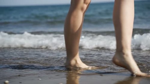 Woman Walks Barefoot on Beach with Gentle Waves