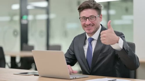 Thumbs Up By Positive Middle Aged Businessman Working in Office