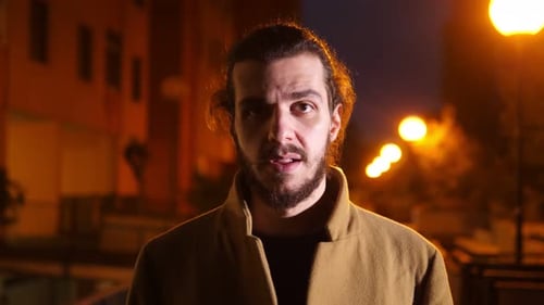 Bearded Man Stands at Night in City