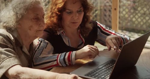Woman Helps Senior with Laptop