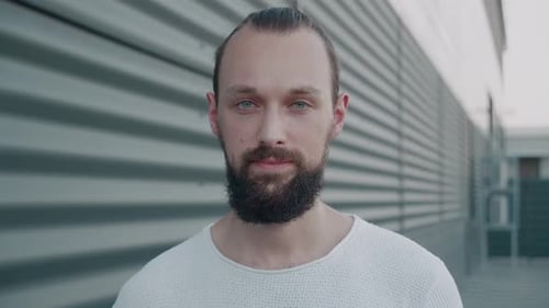 Smiling Bearded Millennial Hipster with Blue Eyes Looking at Camera
