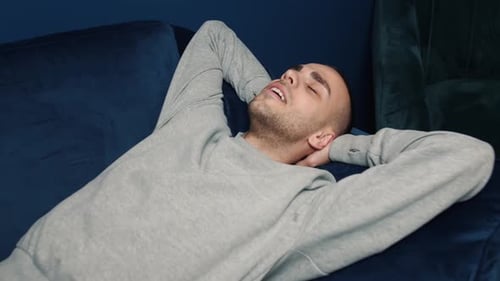 Man Resting on Couch with Hands Behind Head