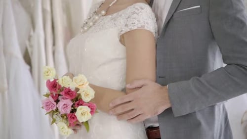 Happy Couple Embrace in Bridal Shop with Dresses