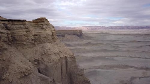 Aerial view flying past cliff viewing the terrain across the desert