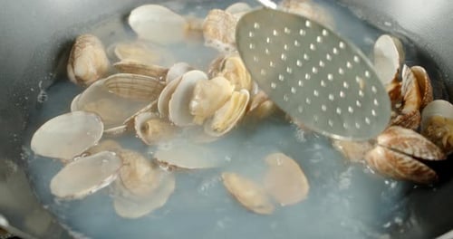 Les moules Vongole sont mélangées dans de l'eau bouillante dans une casserole.