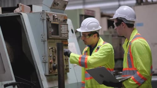Foreman or engineer worker hold laptop and discuss with his co-worker technician