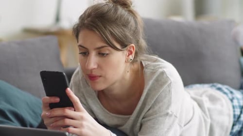 Young Woman Relaxing and Using Smartphone at Home