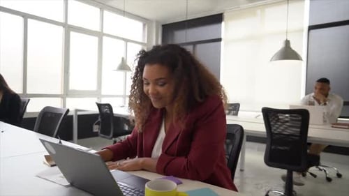 Femme d'affaires travaillant dans un espace de coworking, ayant un appel vidéo sur ordinateur portable