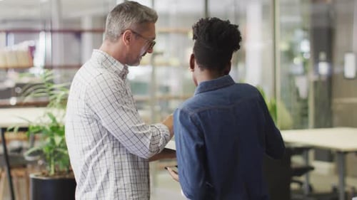 Mature Man and Young Adult Shaking Hands in Office