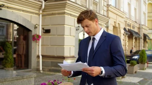 Focused Business Man Reading Documents Outdoors. Thinking Professional