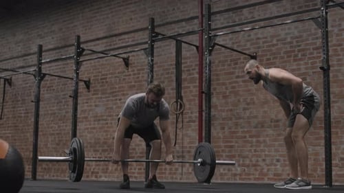 Man Doing Deadlifts With Spotter in Gym